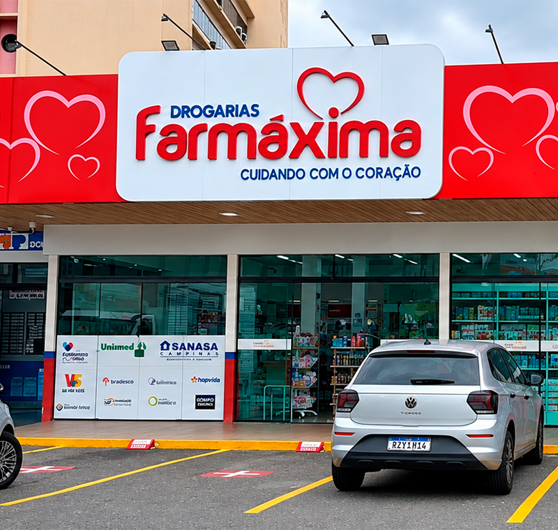 Fachada das Drogarias Farmáxima, com entregador saindo para uma entrega pelo iFood